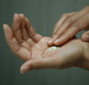 an open hand holding a dollop of AloeGlyC, other hand dipping a finger