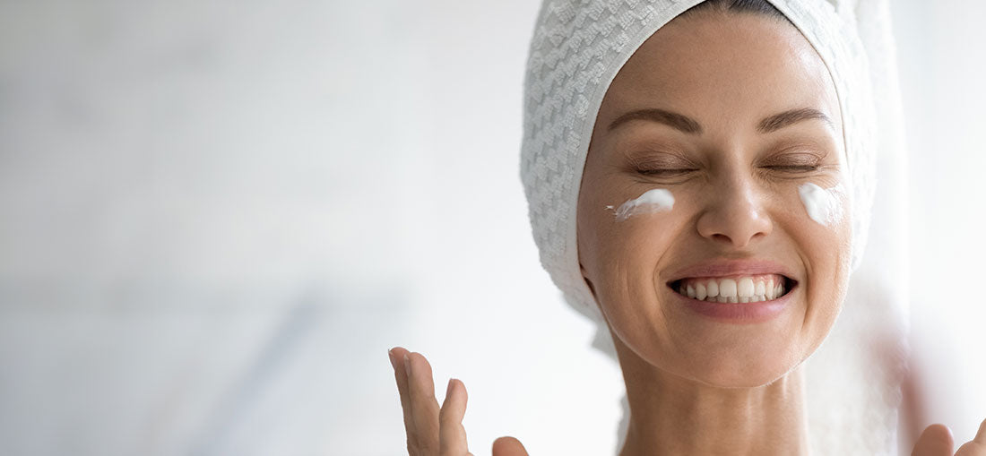 woman with moisturizer on her cheekbones and a big smile on her face