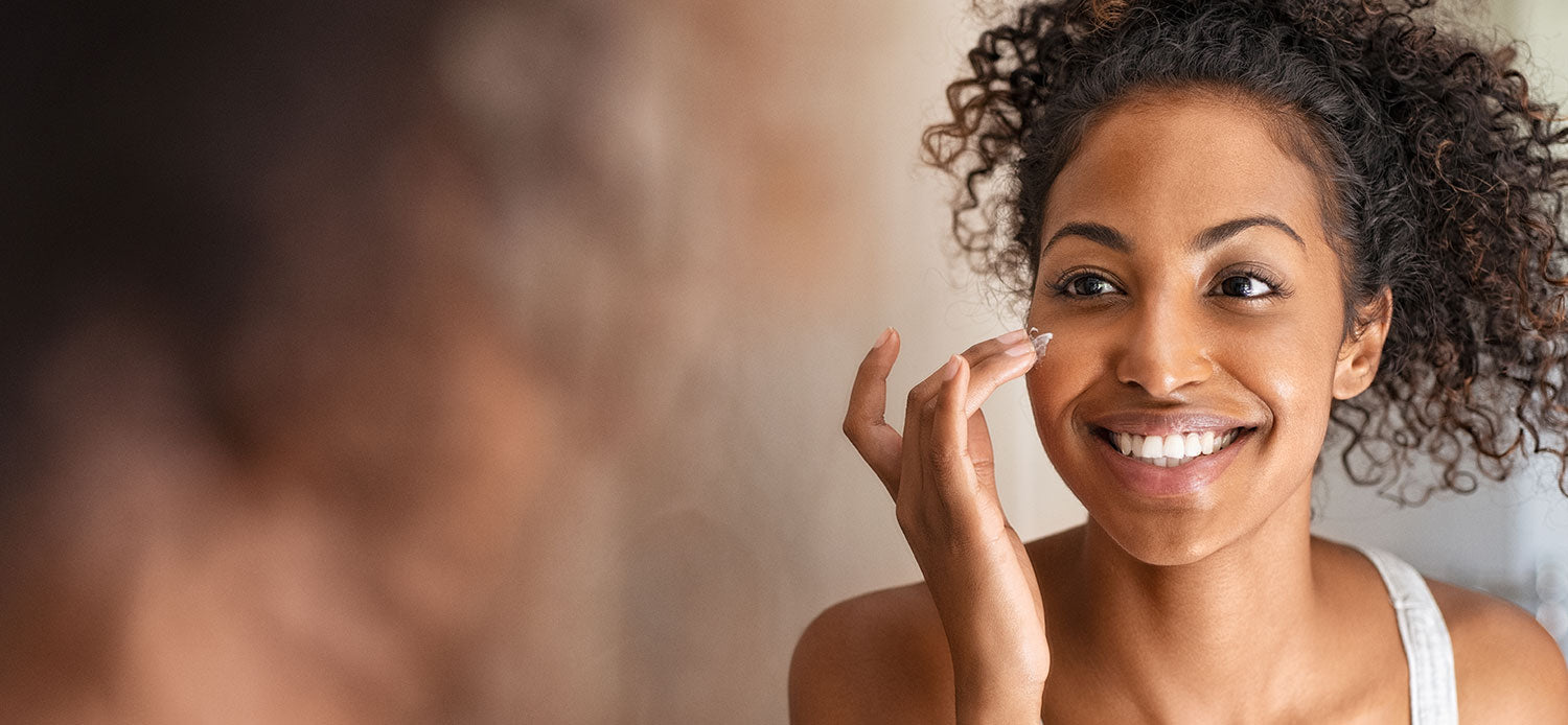 Woman applying skin care product to her cheek and smiling